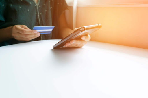 a girl holding a credit card or debit card and looking at a credit card swiping machine